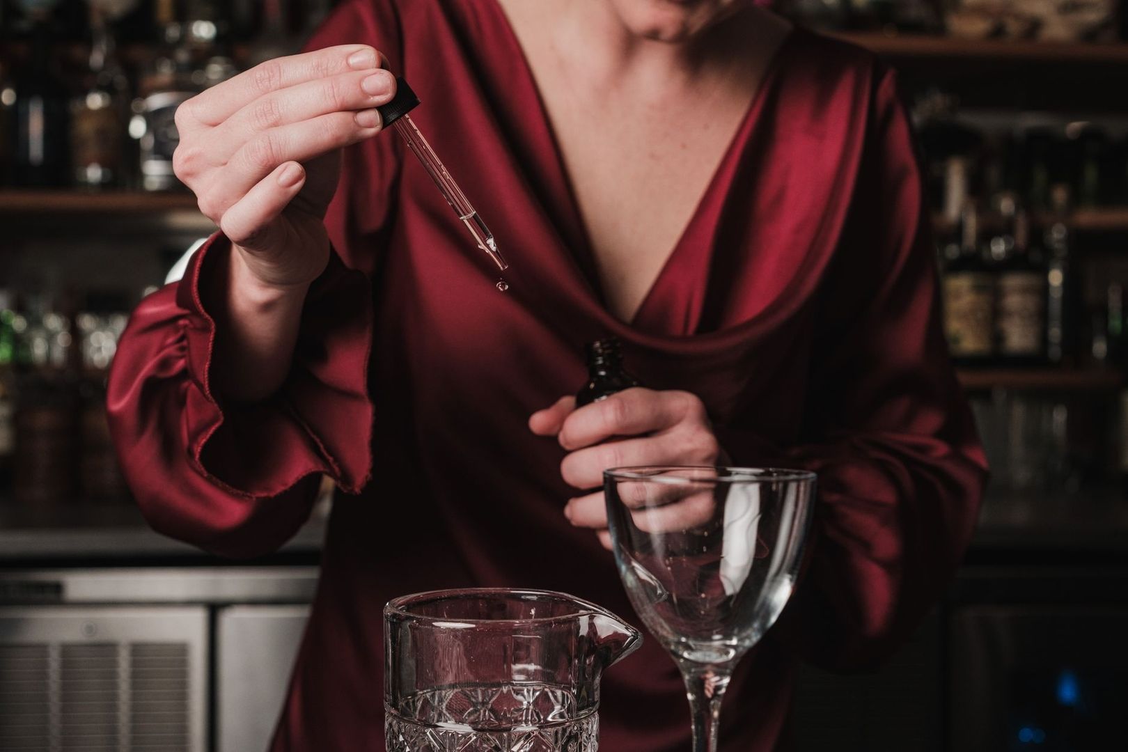 Bartender droppar aromatiska bitters från en pipett i ett glas