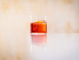 Glas med röd vermouthliknande dryck och apelsinzest på ett bord