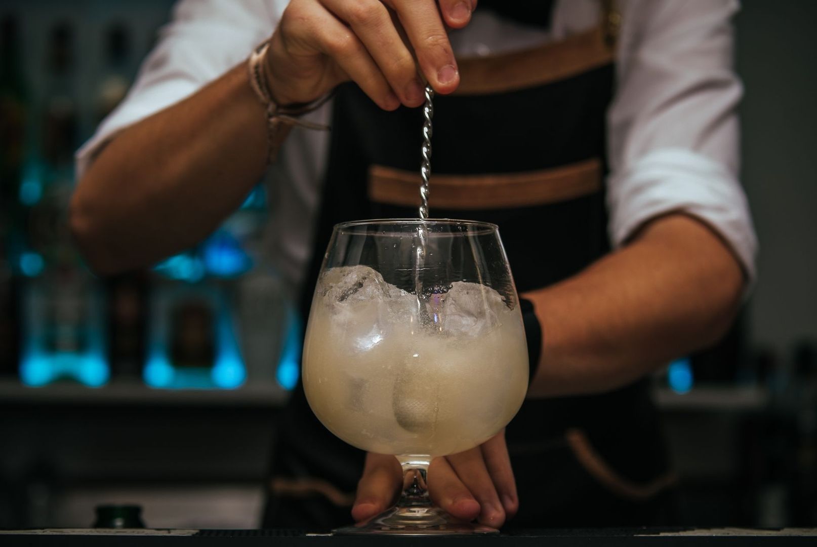 Bartender rör en iskall, ljus cocktail i ett kupat glas